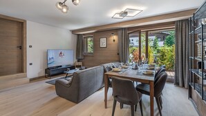 Un salon moderne comprenant un téléviseur, un canapé, une table à manger et des chaises.