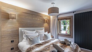 Une chambre moderne avec une tête de lit en bois, un grand lit avec de nombreux oreillers, une couverture moelleuse et une fenêtre avec des rideaux.