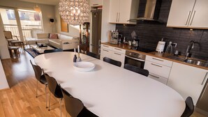 Une cuisine moderne dotée d’un îlot central, d’appareils électroménagers en acier inoxydable et d’un coin repas avec une longue table et des chaises.