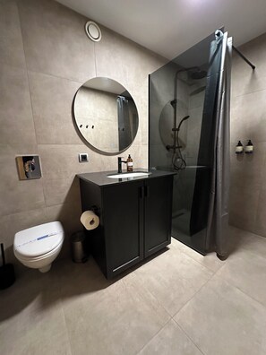 A modern bathroom with a toilet, sink, mirror, and shower. - Perfectly located, very spacious 2 bedroom apartment in the heart of Reykjavik (Reykjavík)