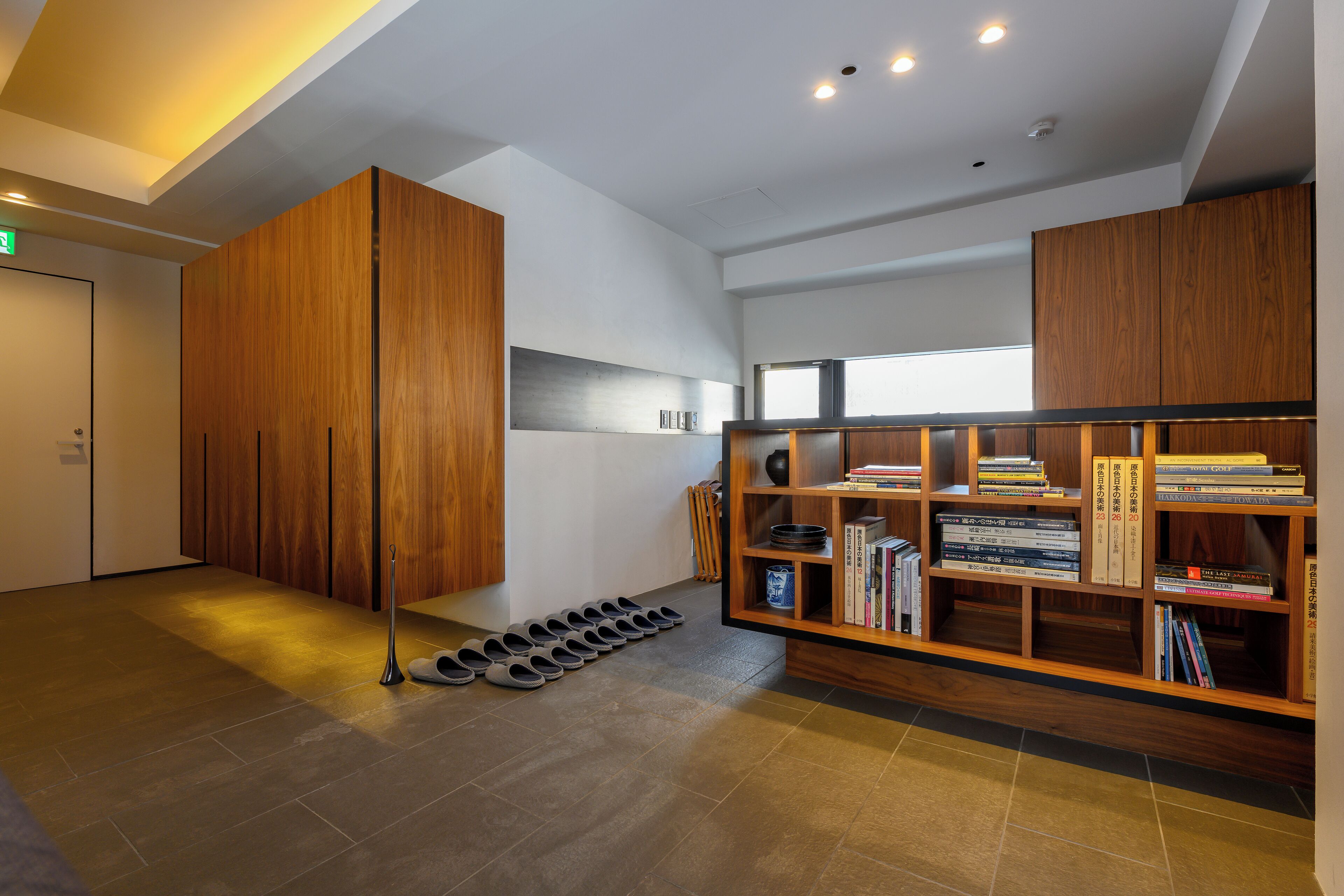 A modern interior with wooden cabinets, a bookshelf, and a shoe rack.