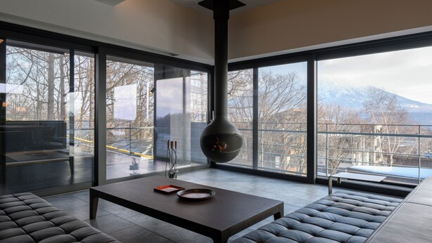 Ein modernes Wohnzimmer mit großem Fenster, Kamin und einer Couch.