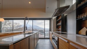 Eine moderne Küche mit einer großen Kochinsel, Holzschränken und Bergblick durch große Fenster.