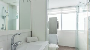 Een moderne badkamer met een grote spiegel, een witte wastafel en een douchecabine van glas.