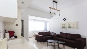 Een moderne woonkamer met een bruine bank, een salontafel en een keuken met een fornuis.
