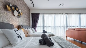 Habitación de hotel moderna con una cama grande, un sofá y vistas al exterior a través de cortinas translúcidas.