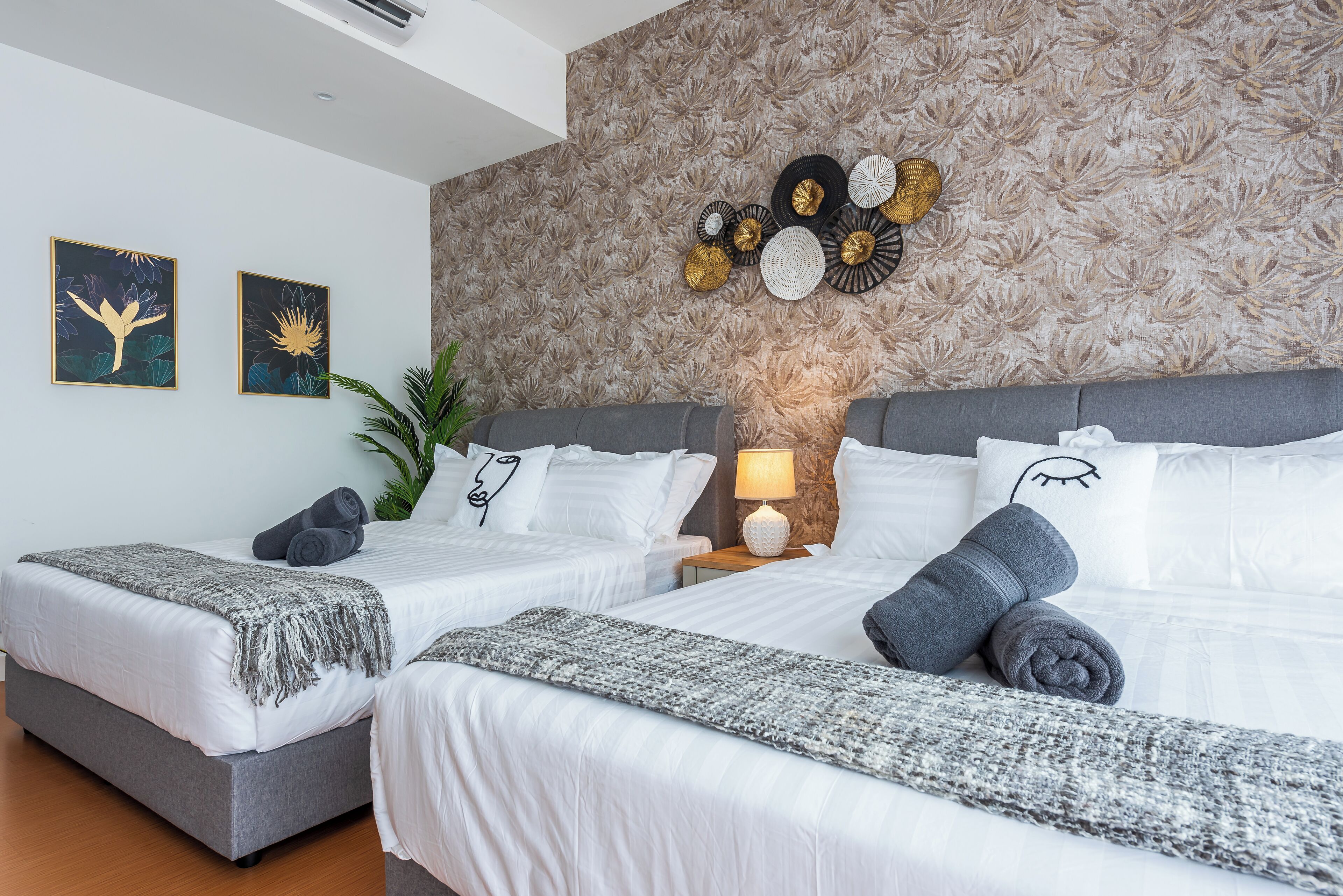 A hotel room with two beds, a patterned wallpaper, and decorative wall art.