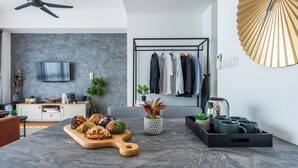 Una cocina moderna con encimera de mármol, tabla de madera con pasteles, cafetera y perchero.