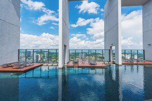 Una piscina infinita en la azotea con agua cristalina y azul, rodeada de pilares blancos y con vistas panorámicas de la ciudad.