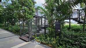 Una escalera con barandilla metálica, rodeada de abundante vegetación y un sendero.