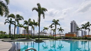 Una piscina rodeada de palmeras y edificios modernos al fondo.