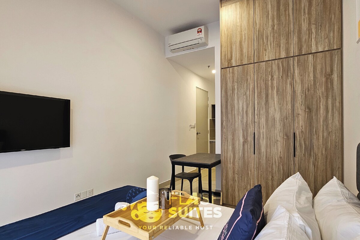 A modern hotel room with a flat-screen TV, a wooden wardrobe, a small table with a tray, and a bed with pillows.