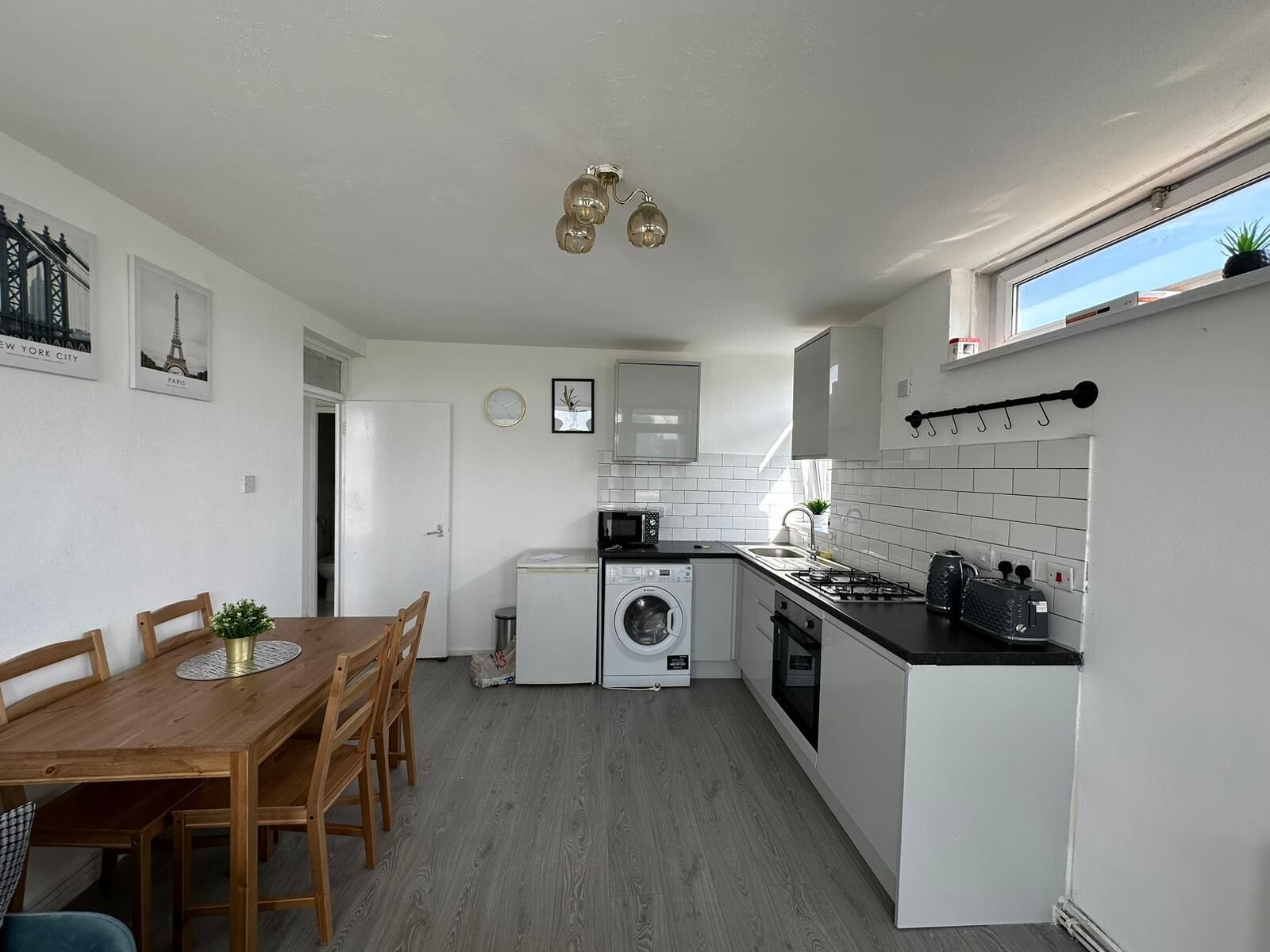 Une cuisine compacte comprenant un coin repas, un lave-linge et un petit réfrigérateur.