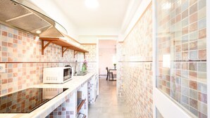A modern kitchen with a microwave, sink, and wooden shelves. - 2 bedroom, city and sea (Fuengirola)