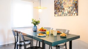 A dining area with a table set for breakfast, including croissants, fruit, and juice. There are chairs around the table, and a decorative vase with flowers. - 2 bedroom, city and sea (Fuengirola)