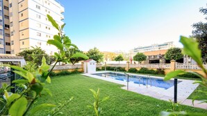 A well-maintained outdoor area with a swimming pool, surrounded by a neatly trimmed lawn and a low wall. - Terrace, swimming pool, parking (Fuengirola)