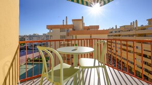 A balcony with a round table and chairs, a small potted plant, and a view of surrounding buildings. - Terrace, swimming pool, parking (Fuengirola)