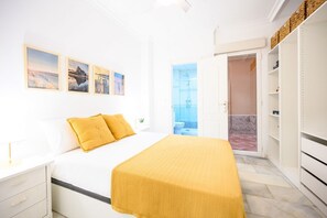 Un dormitorio con cama, armario y baño visible a través de una puerta abierta.