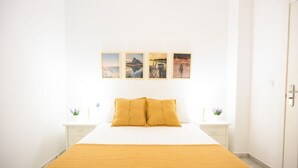 A bedroom with a bed, two bedside tables, a nightstand, and a door. - 2 min to the beach. Modern apartment (fuengirola)