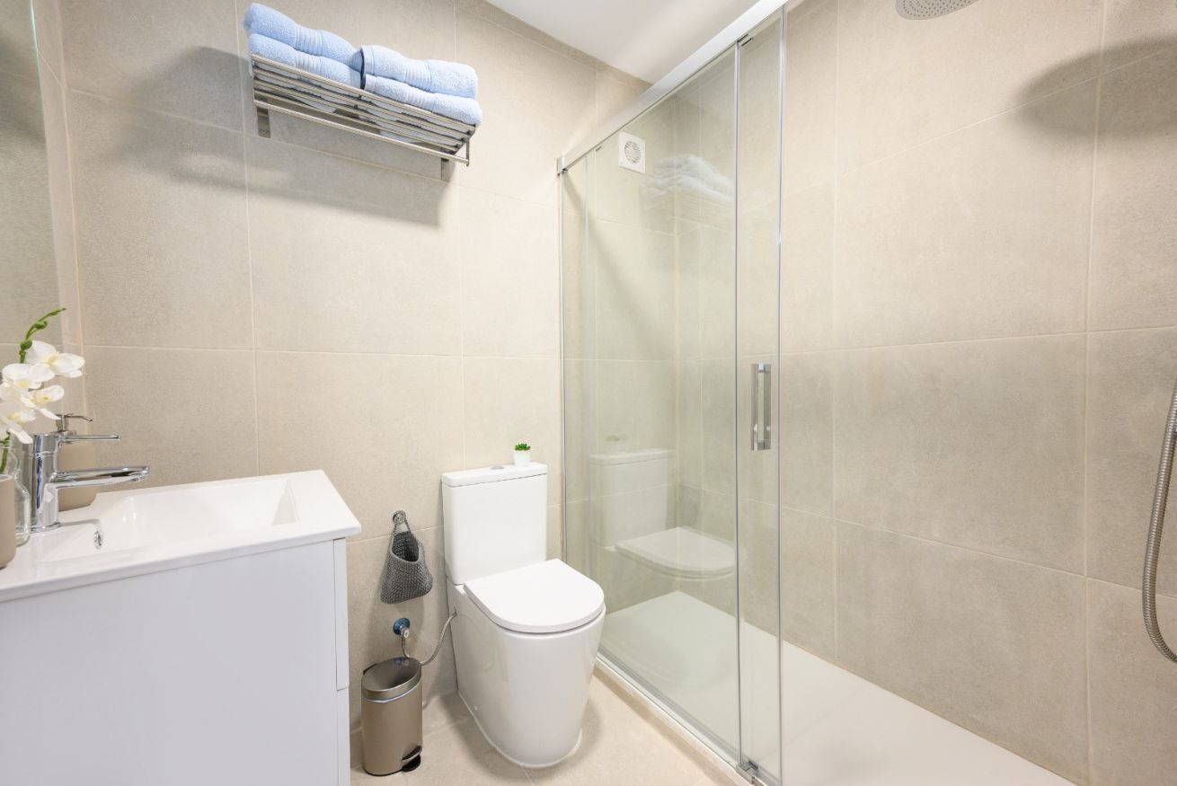 Une salle de bain moderne avec une douche à parois de verre, un lavabo blanc et des toilettes.