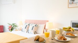 A hotel room with a bed, bedside table with breakfast items, and a TV. - New Studio. Terrace & pool by 10ToSea (Fuengirola)