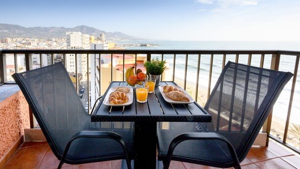 A balcony with a table set for breakfast, overlooking a coastal city and mountains. - Sea & Mountain views from a 10th floor studio with terrace by 10ToSea (Fuengirola)