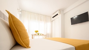 A hotel room with a bed, a TV mounted on the wall, and a window with curtains.