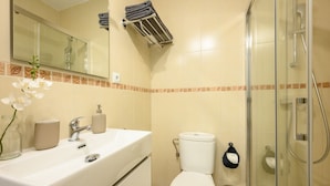 A bathroom with a sink, mirror, toilet, and glass shower enclosure.