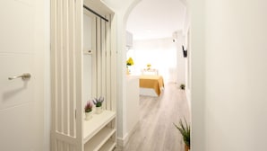 A hallway with a white door, a white wardrobe, and a bed with a yellow bedspread in the background.
