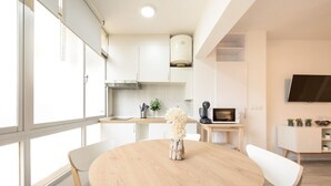 A modern kitchen with white cabinets, a round wooden table, and a vase with flowers. - Nice studio at 3min to the beach new refurbished by 10ToSea (Fuengirola)