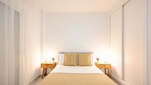 A neatly arranged bedroom with a large bed, two bedside tables, and a window on one side.