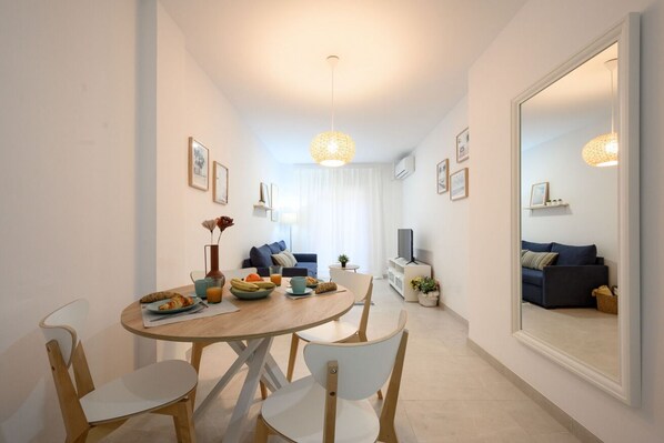 Un coin repas moderne avec une table ronde, des chaises blanches et une table préparée pour le petit-déjeuner.