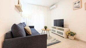 A modern living room with a sofa, a TV, a small table with a plant, and a decorative basket.