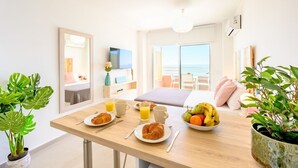 Desayuno preparado con una mesa, alimentos para el desayuno y vista al océano.