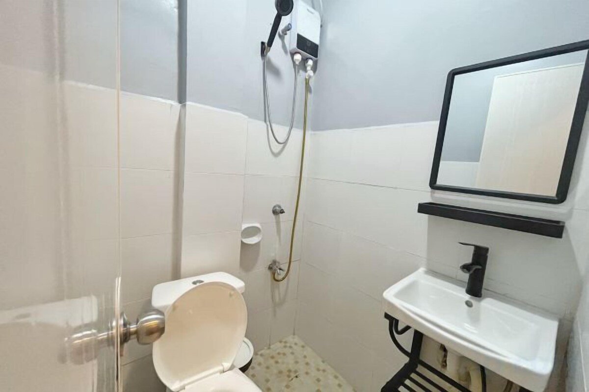 A bathroom with a toilet, sink, mirror, and shower.