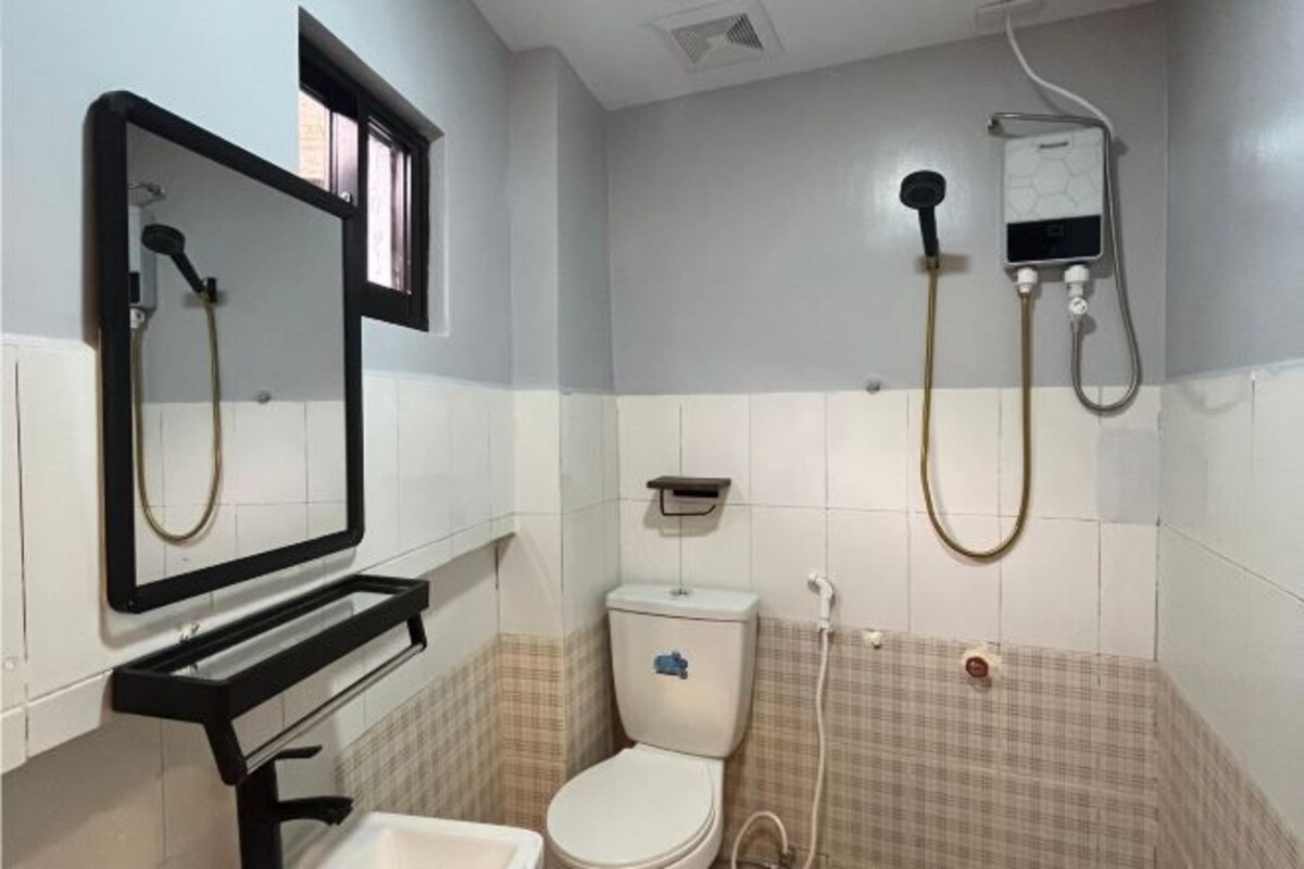 A bathroom with a toilet, a sink, a mirror, and a shower unit.
