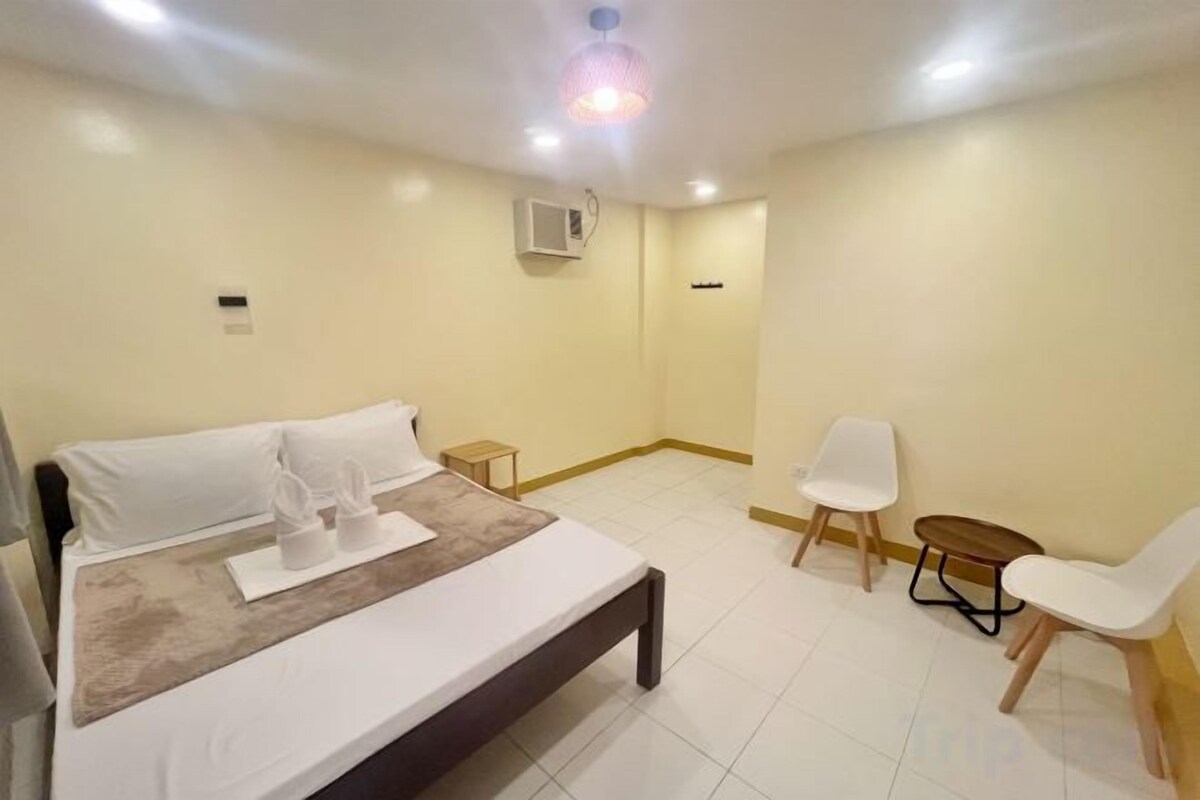 A hotel room with a bed, bedside tables, a chair, and a small table.