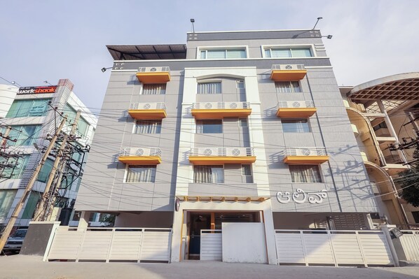 A multi-story building with balconies, a gated entrance, and a sign in a local language.