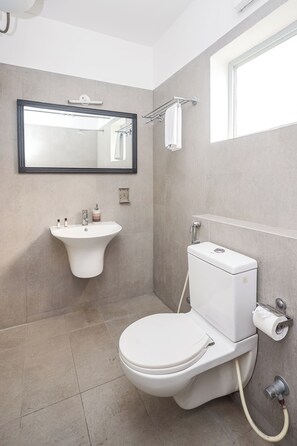 A bathroom with a white sink, a toilet, a mirror, and a window.