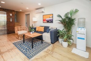 Una sala de estar con sofá, mesa de centro y plantas en macetas.