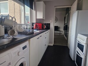 Une cuisine compacte équipée d’un lave-linge, d’un four à micro-ondes et d’un réfrigérateur.