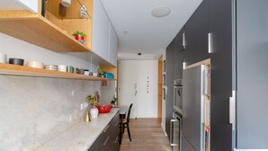 Une cuisine moderne avec un plan de travail en marbre, des étagères en bois et un réfrigérateur noir.