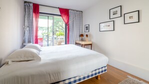 Une chambre à coucher avec un grand lit, un bureau et une fenêtre avec des rideaux.