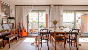 Un espace repas avec un piano, des guitares et une table entourée de chaises.