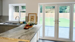 A modern kitchen with a marble countertop, a sink, and a large sliding glass door leading to a backyard. - 4 Beds House Coventry Sleep 7 With 3parking Spaces (Coventry)