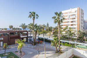 A hotel with multiple floors, palm trees, and a clear sky.