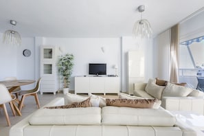 Uma sala de estar moderna com sofá, mesa de jantar e televisão.