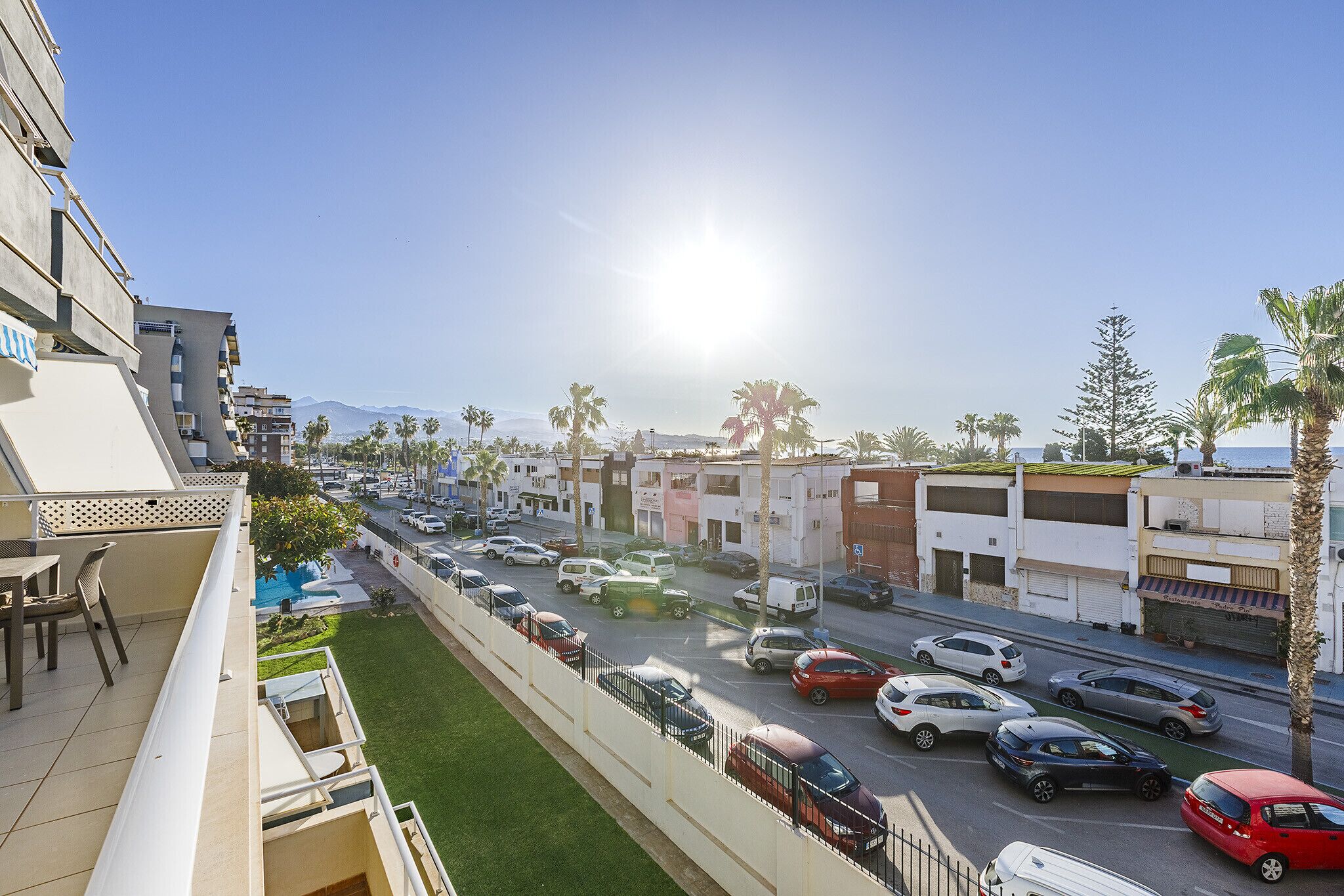 Un quartier résidentiel avec vue sur la rue, comprenant des voitures garées et des immeubles.