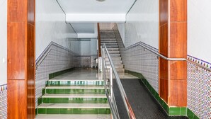 A staircase with green and white tiles, metal railings, and wooden columns.