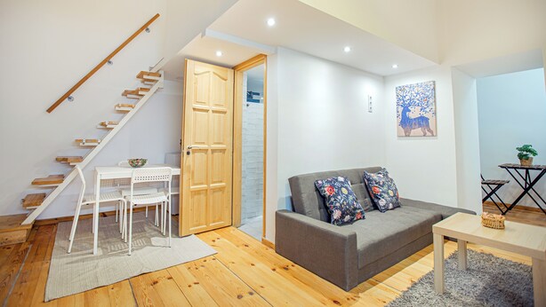A modern living room with a staircase, grey sofa, and wooden flooring. - Cute gallery flat in Budapest Pearl  (Budapest)